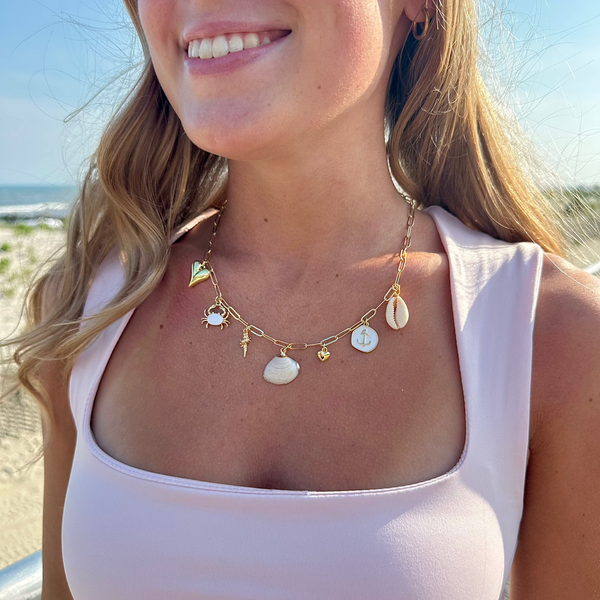 Woman wearing a gold necklace with shell pendants on a beach