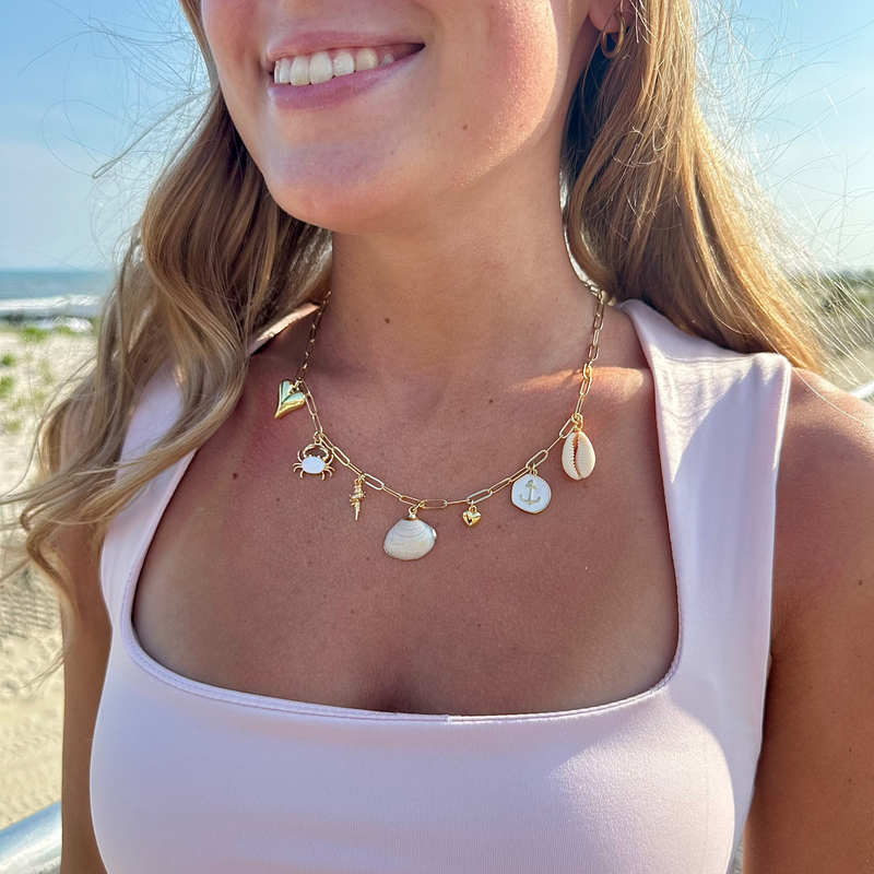 Woman wearing a gold necklace with shell pendants on a beach