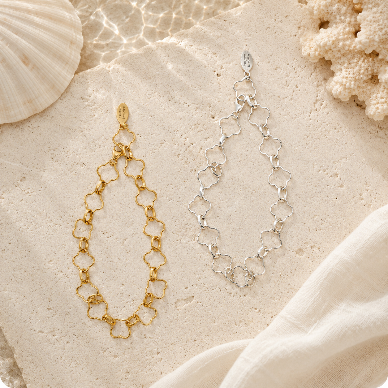 Gold and silver chain earrings on a sandy surface with shells and coral.