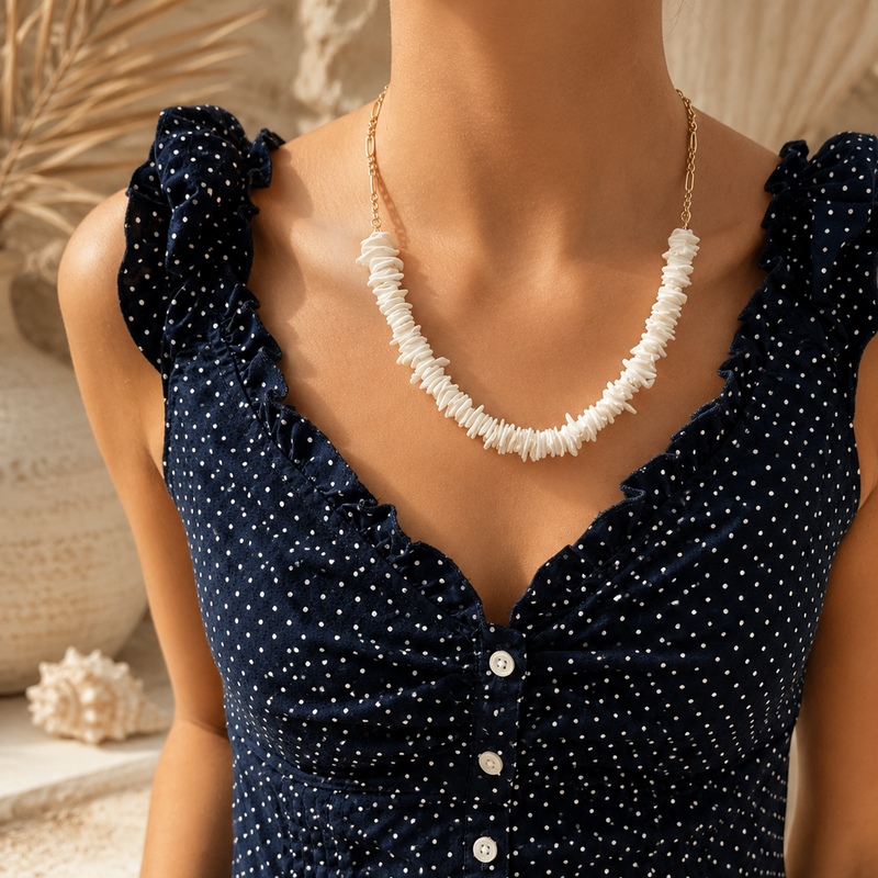 Navy blue dress with white buttons and a white necklace on a neutral background