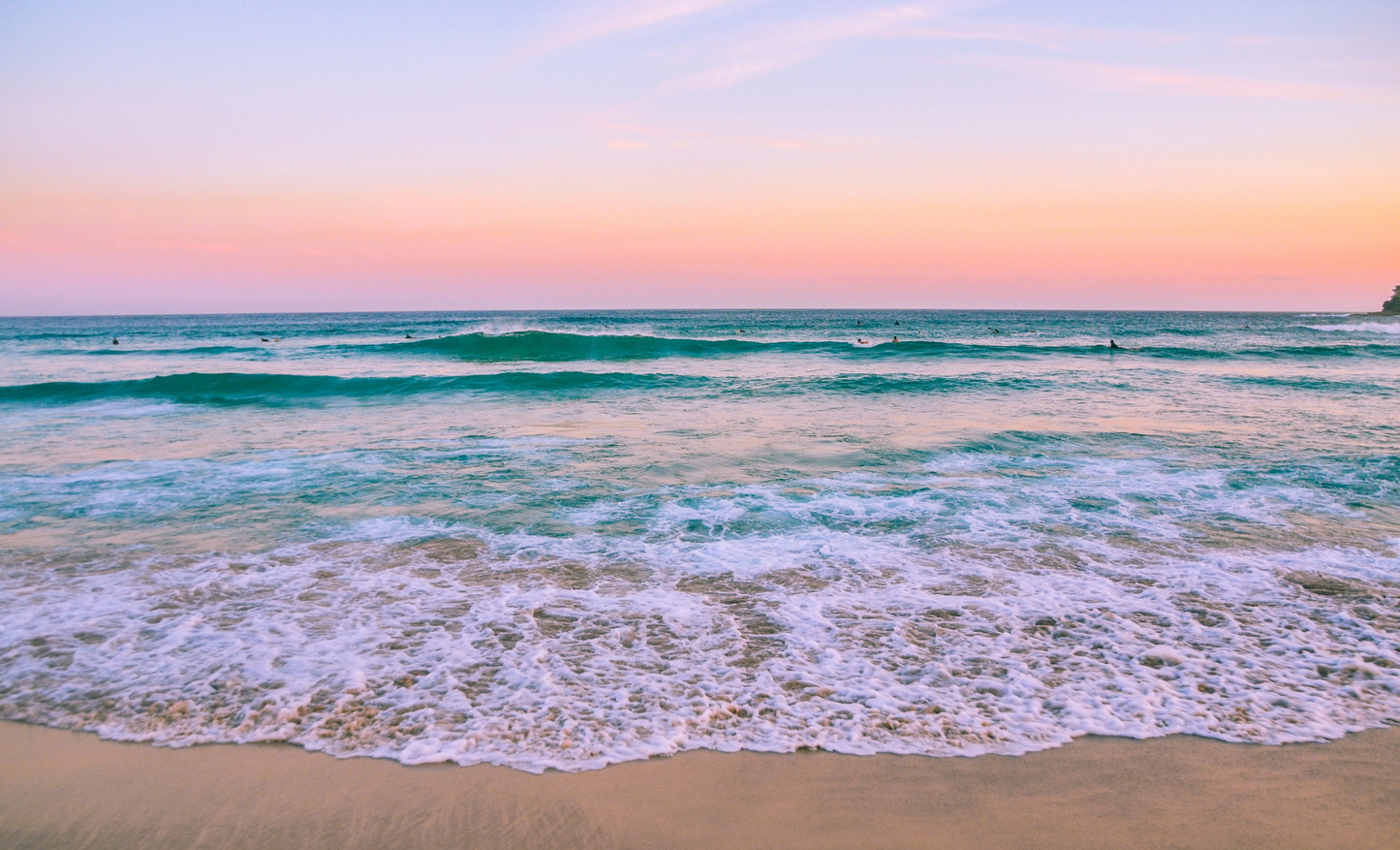 Beach scene with waves and a colorful sunset sky