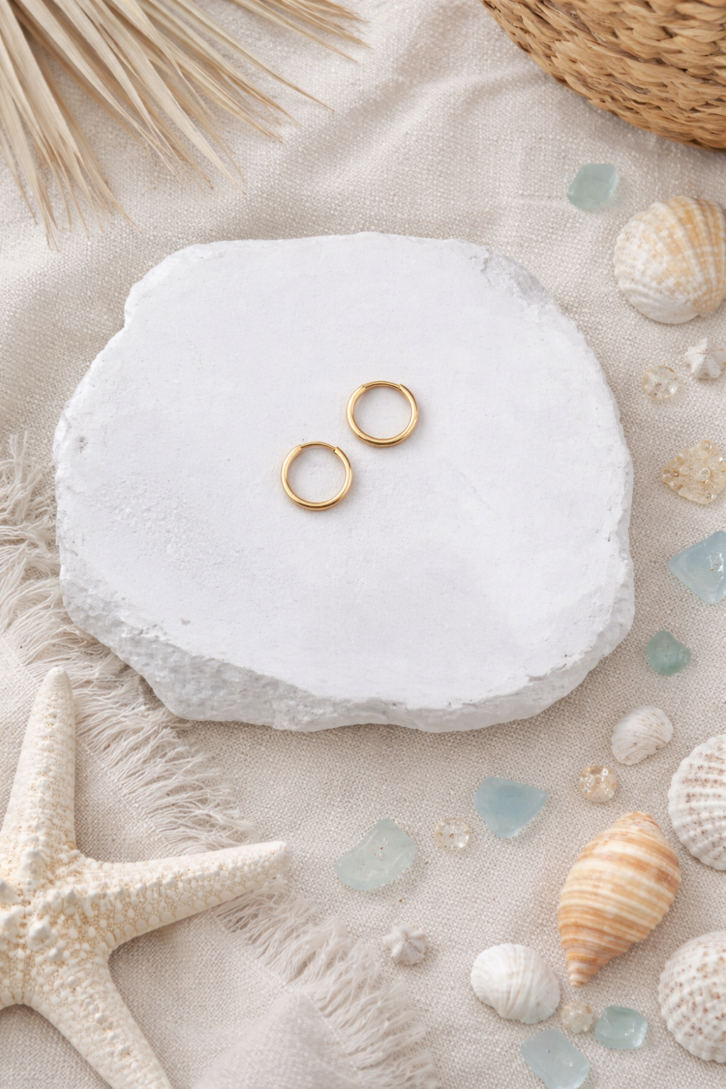 Gold rings on a white shell with beach-themed decor including shells and starfish.