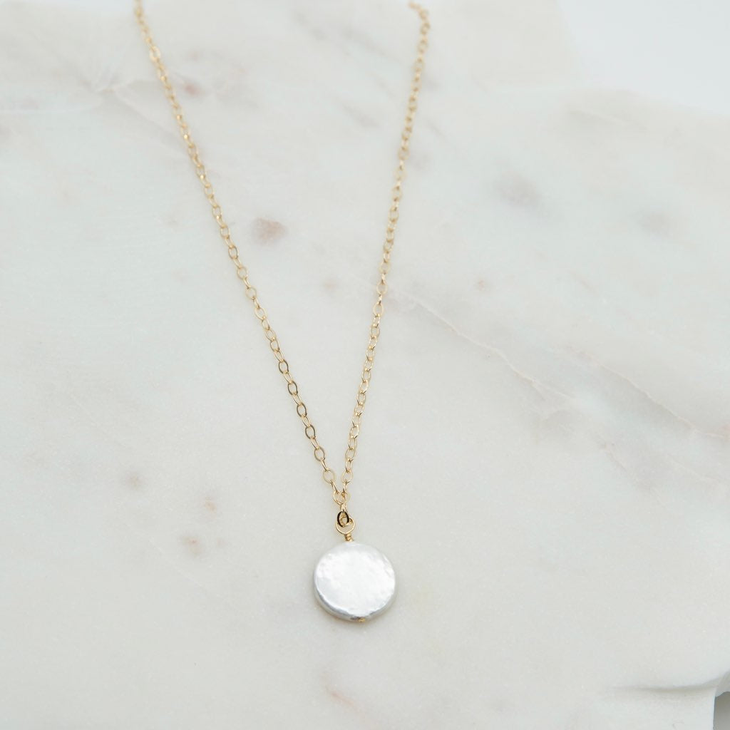 hand wrapped white coin pearl pendant on a gold chain.