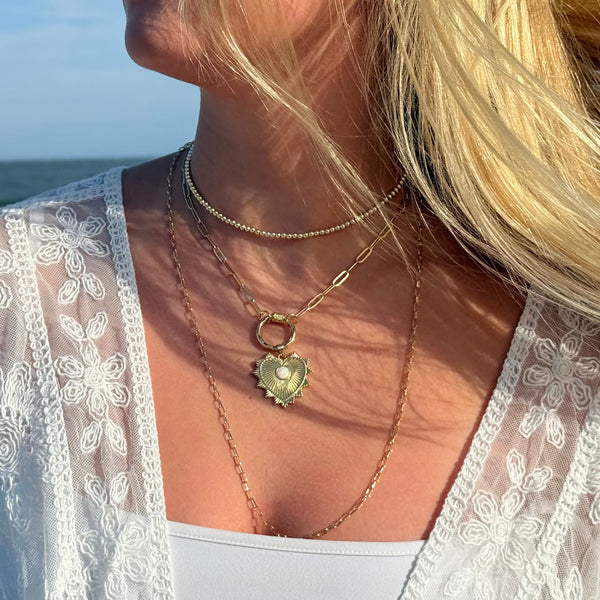 Woman wearing a white lace cover-up with a necklace by the ocean
