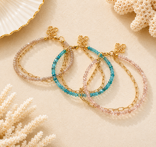 Three beaded and chain bracelets on a sandy background