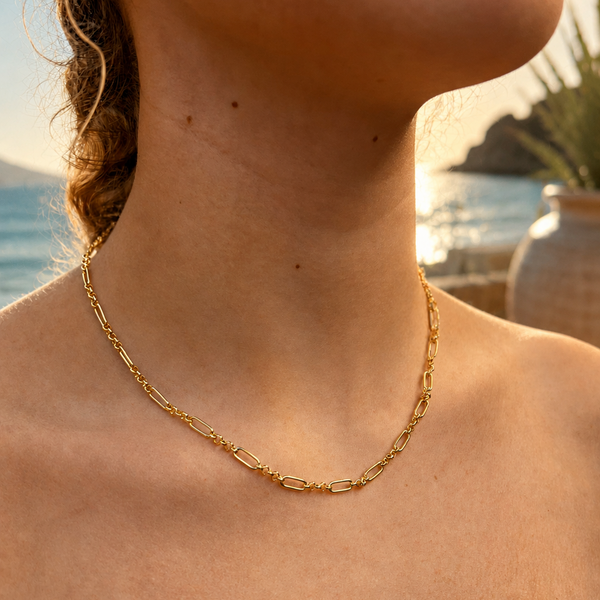Gold chain necklace worn by a person with a scenic background