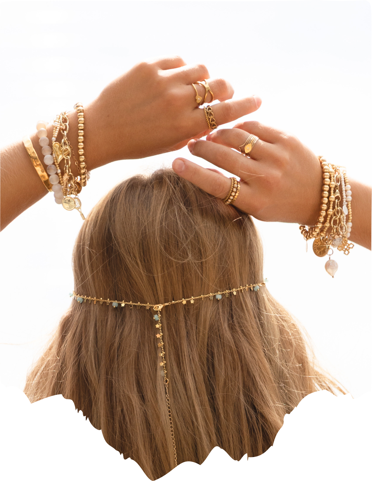 Model holding hands over head displaying stacks of gold and gemstone beaded bracelets.