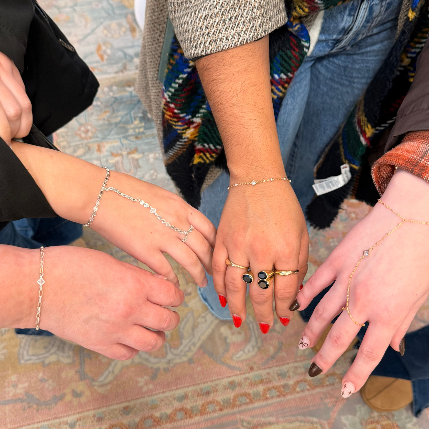 Close-up of hands with payton permanent bracelets and hand chanins, all featuring our diamond shaped cz connector charms.