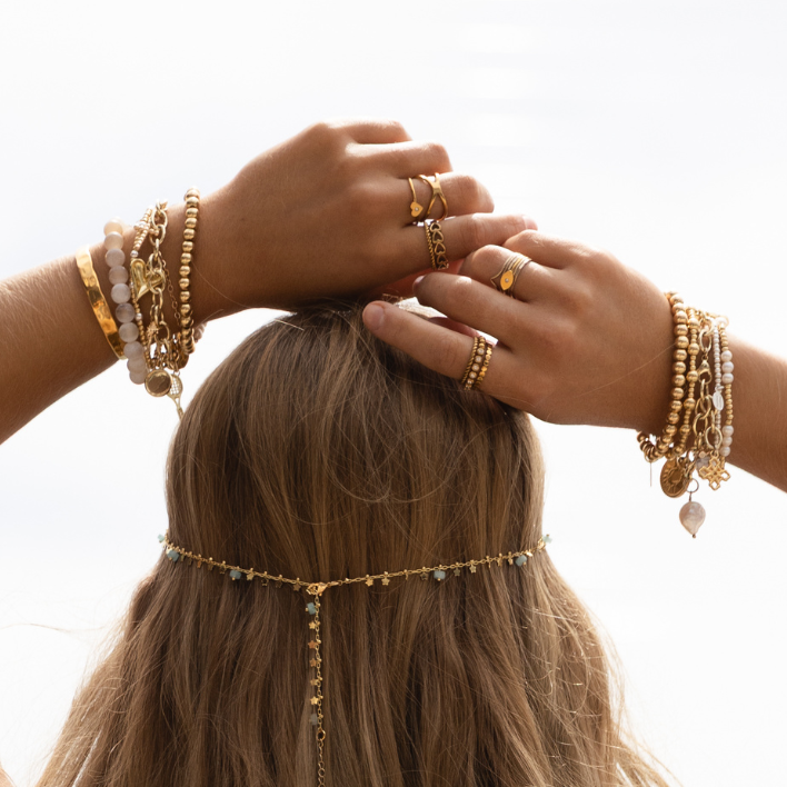 Woman with long hair wearing a Payton multiway necklace, multiple bracelets and rings on a blurred background