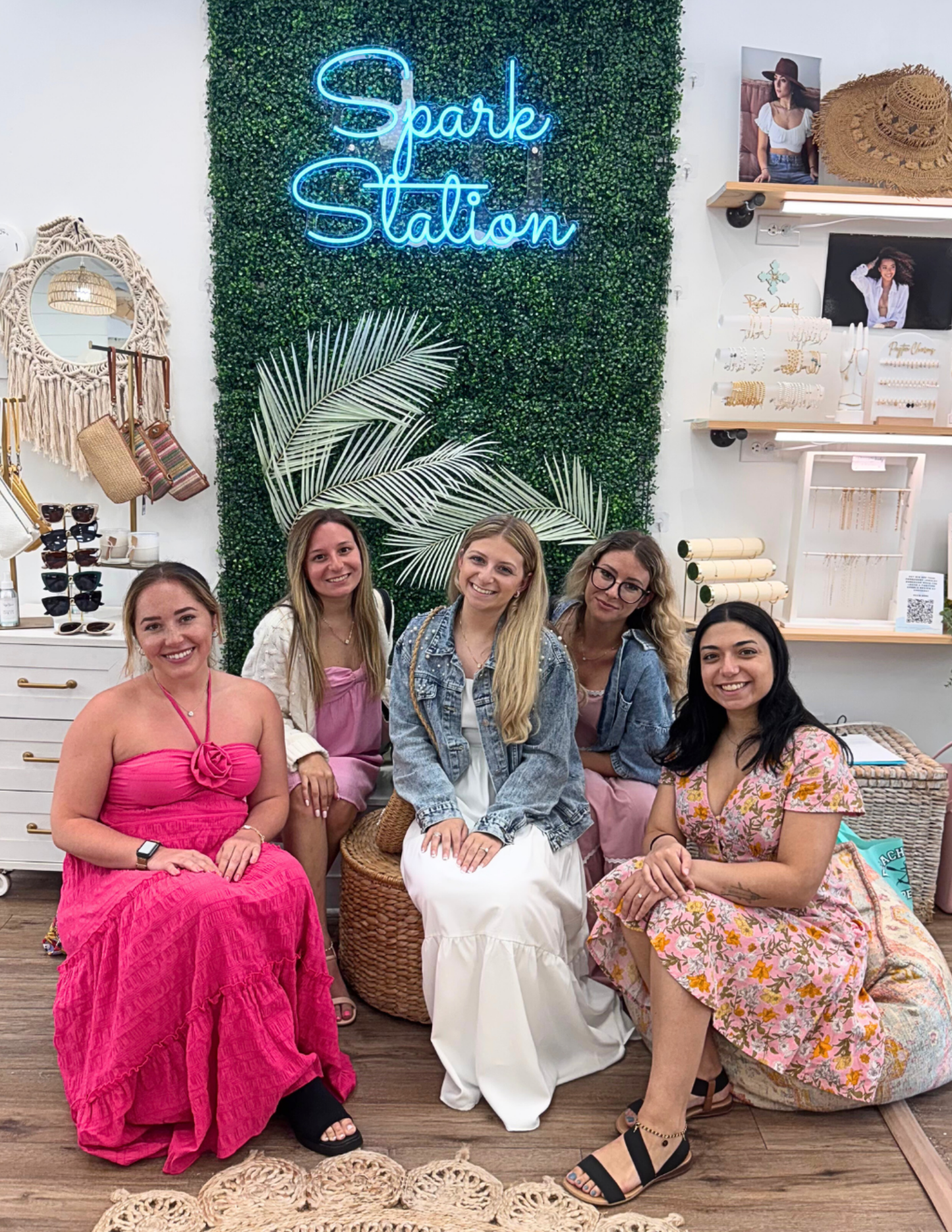 Group of women posing in front of a 'Spark Station' neon sign with decorative elements.