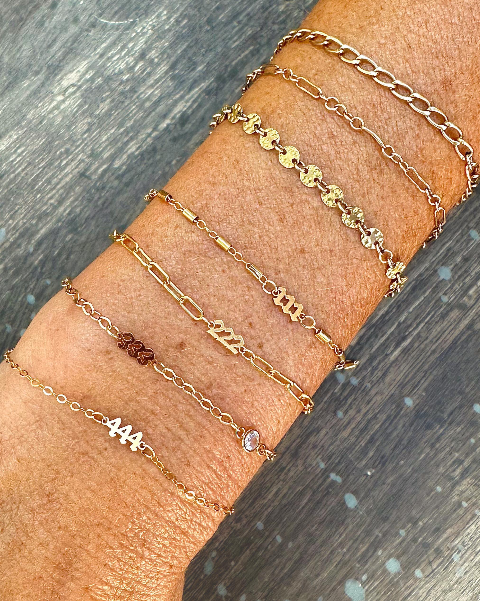 Multiple permanent jewelry bracelets with angel number connector charms. 