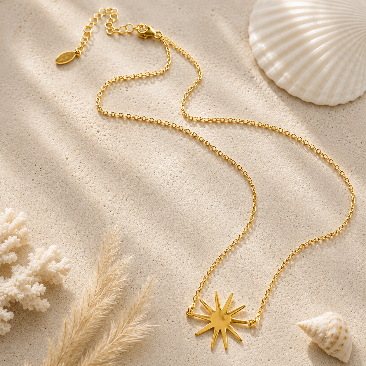 gold necklace with starburst pendant on a sandstone background with coral and shells.