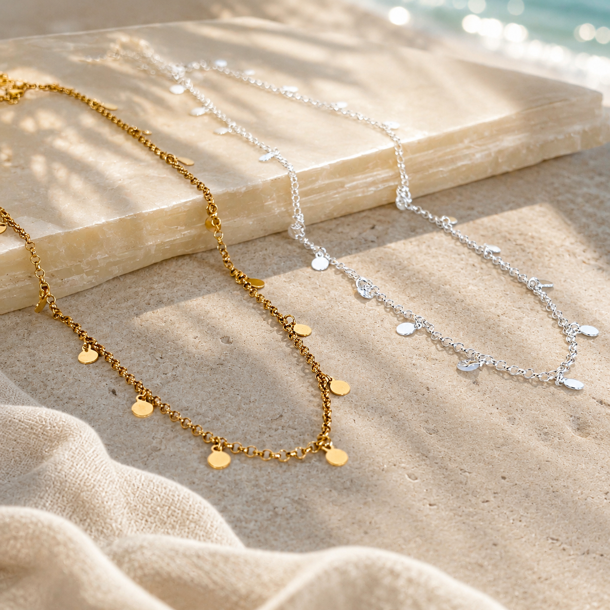 silver and gold tag necklaces displayed on a sandstone background