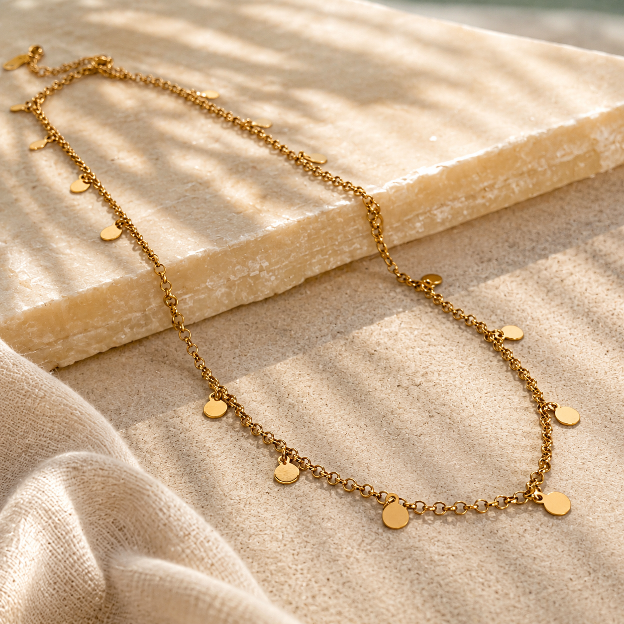 gold tag necklace displayed on a sandstone background