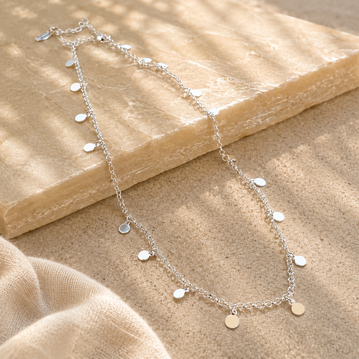 silver tag necklace displayed on a sandstone background