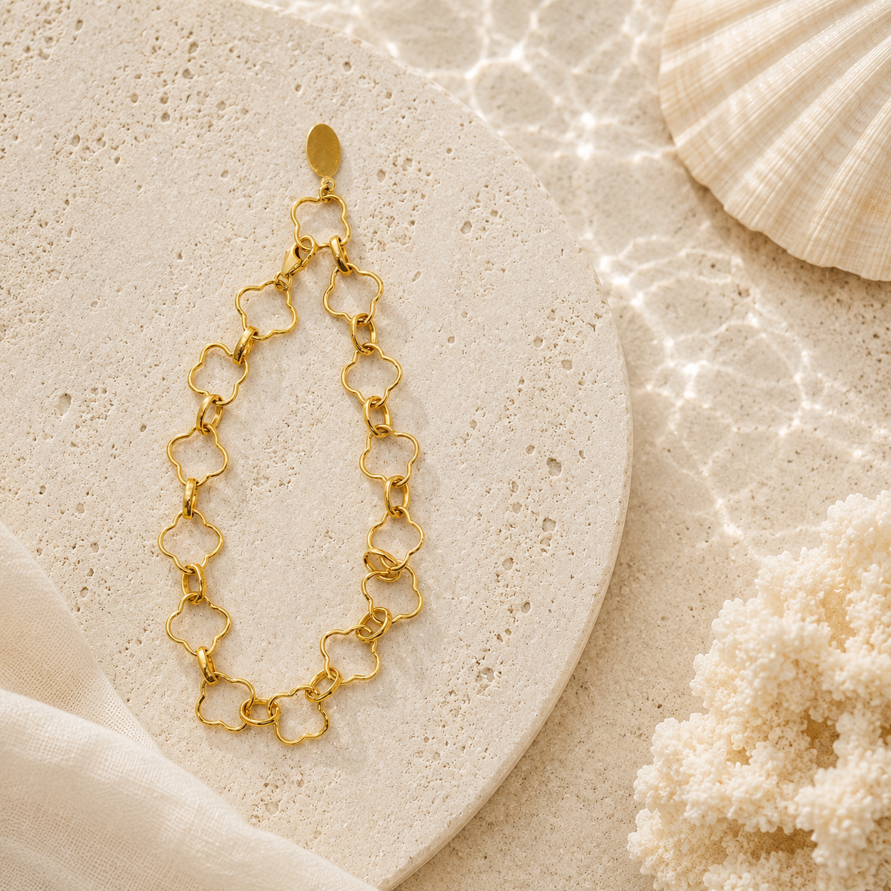 Gold chain bracelet on a textured stone surface with a shell and coral