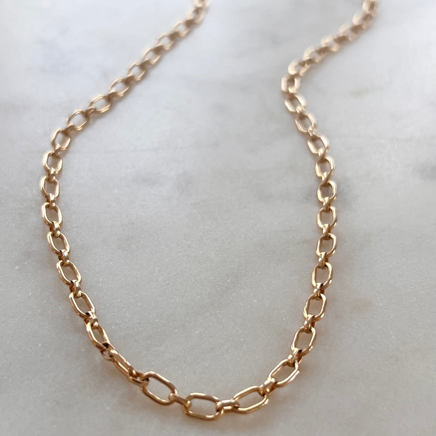 A gold-colored necklace laid out on a surface.