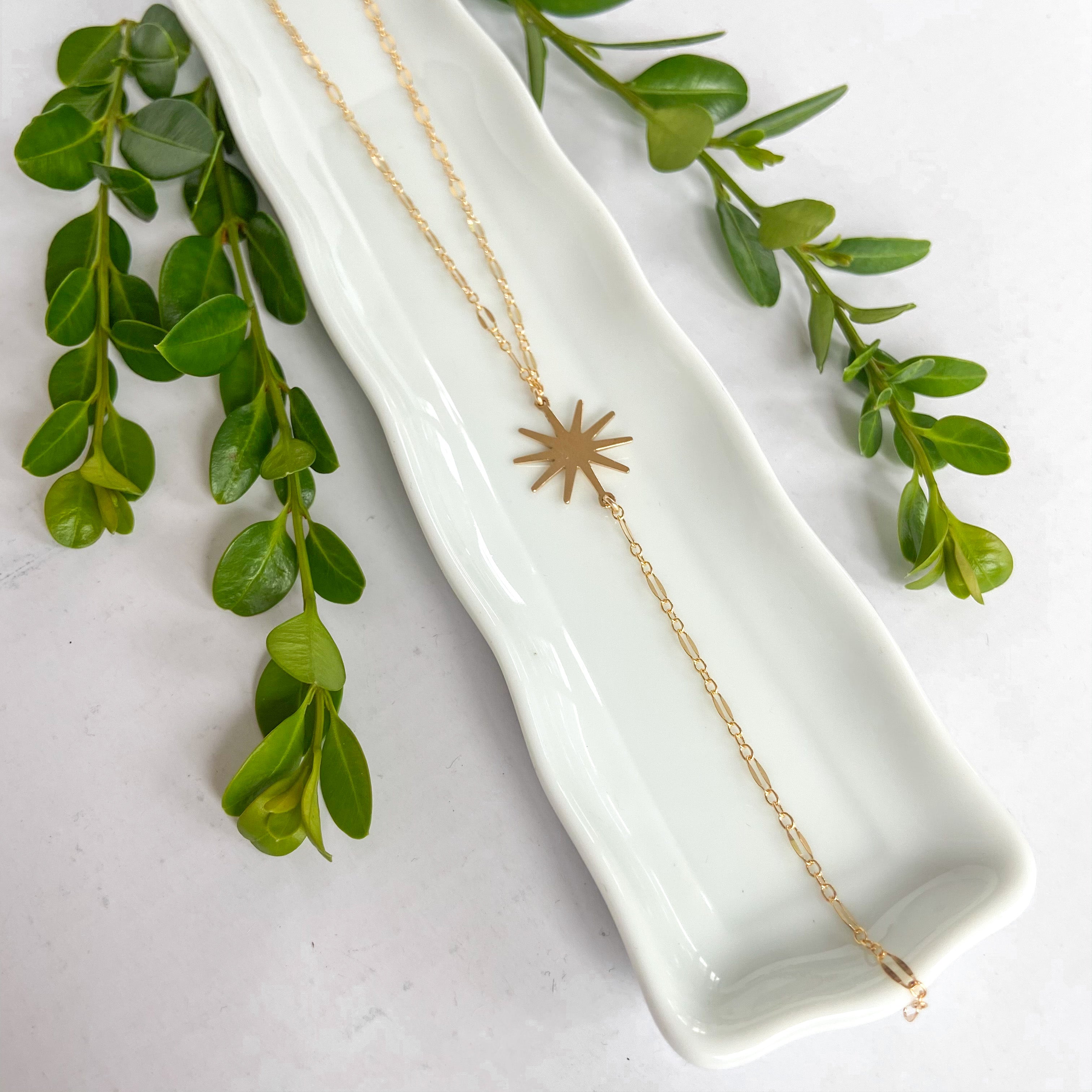 gold drop necklace featuring a starburst pendant 