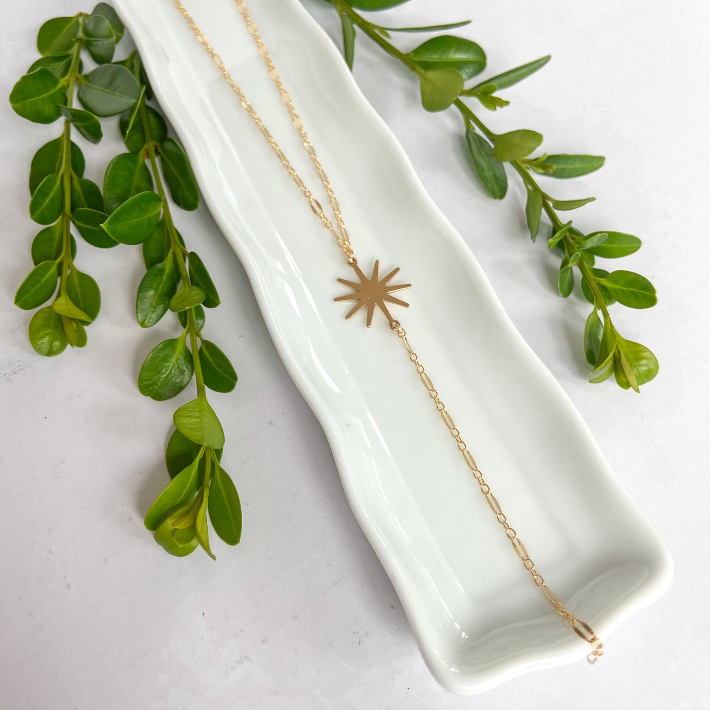 gold drop necklace featuring a starburst pendant 