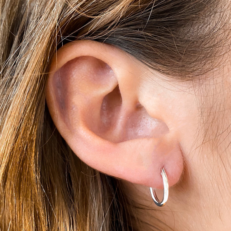 A close-up image of a person wearing a small hoop earrings.